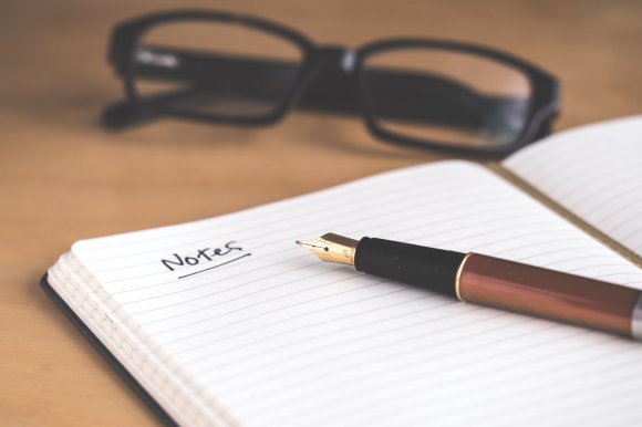 image of glasses pen and notebook symbolising meeting and taking notes