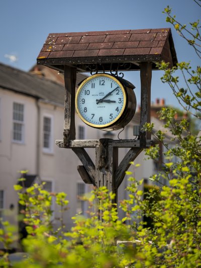 Zoom photo of the village clock on the High Street which hangs within its own little roofed pedestal